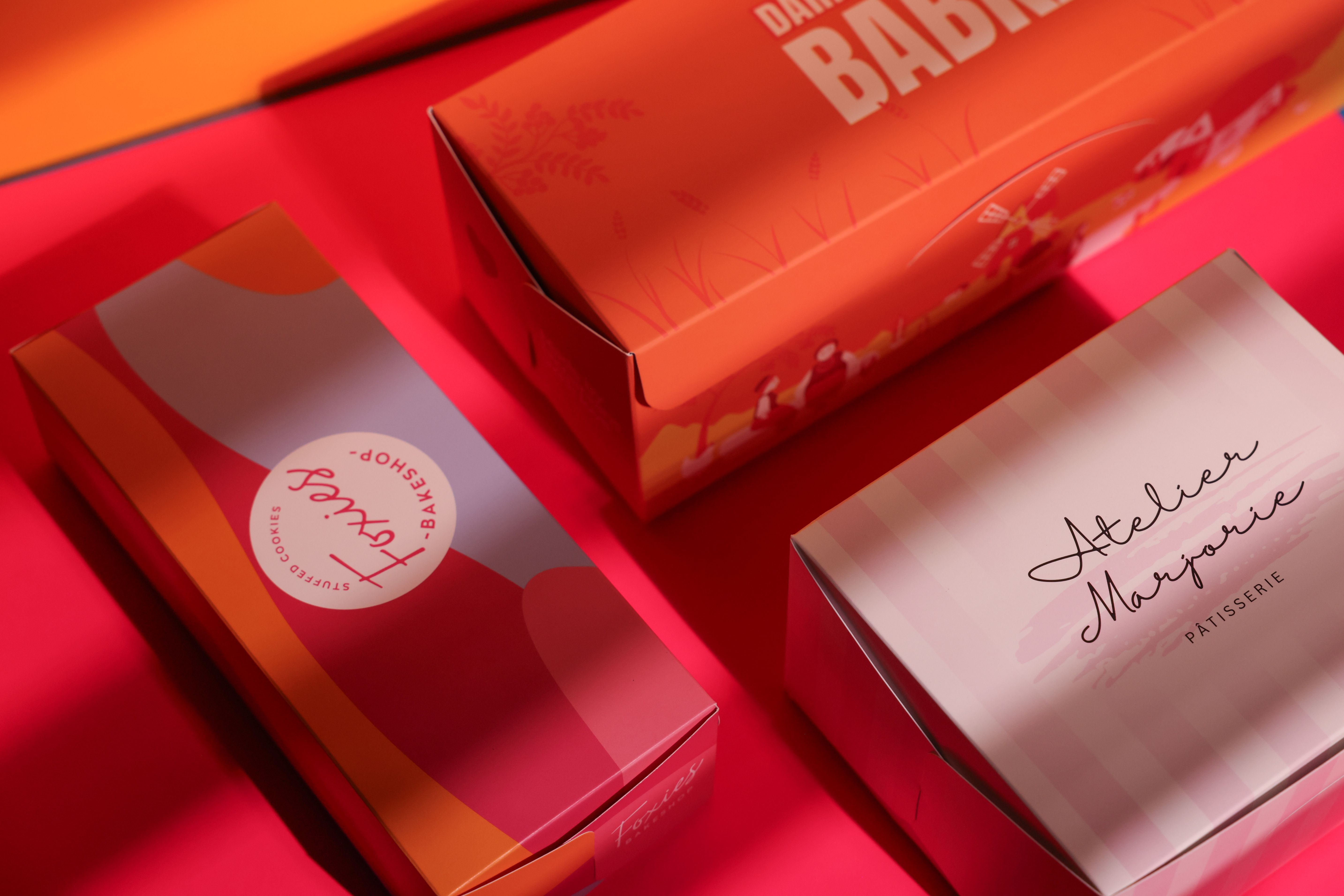 Bakery boxes with varied logos, illustrations, and color schemes.